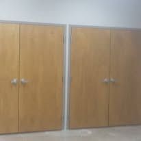 Two pairs of light brown wooden doors with silver handles.