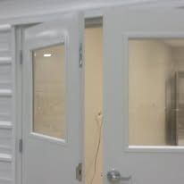 White double doors, one ajar, with glass windows, leading to a room; a power cord is visible.