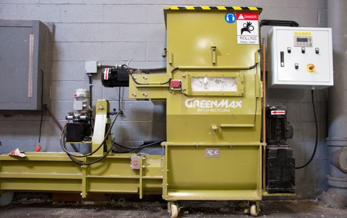 A green max machine is sitting in front of a brick wall.