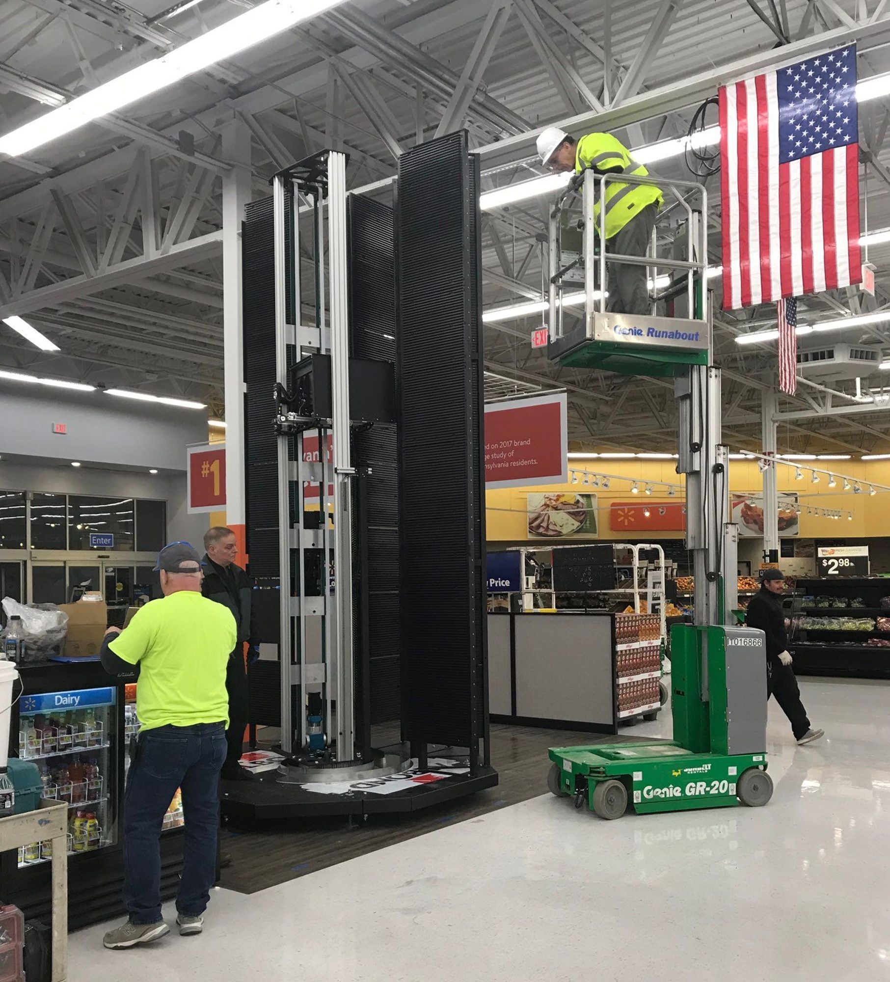 A man on a lift in a store with an american flag hanging from the ceiling