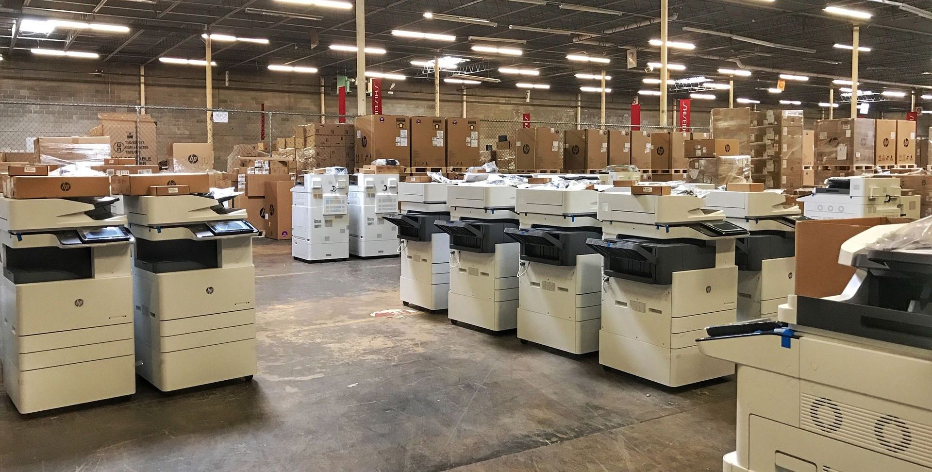 A large warehouse filled with lots of printers and boxes