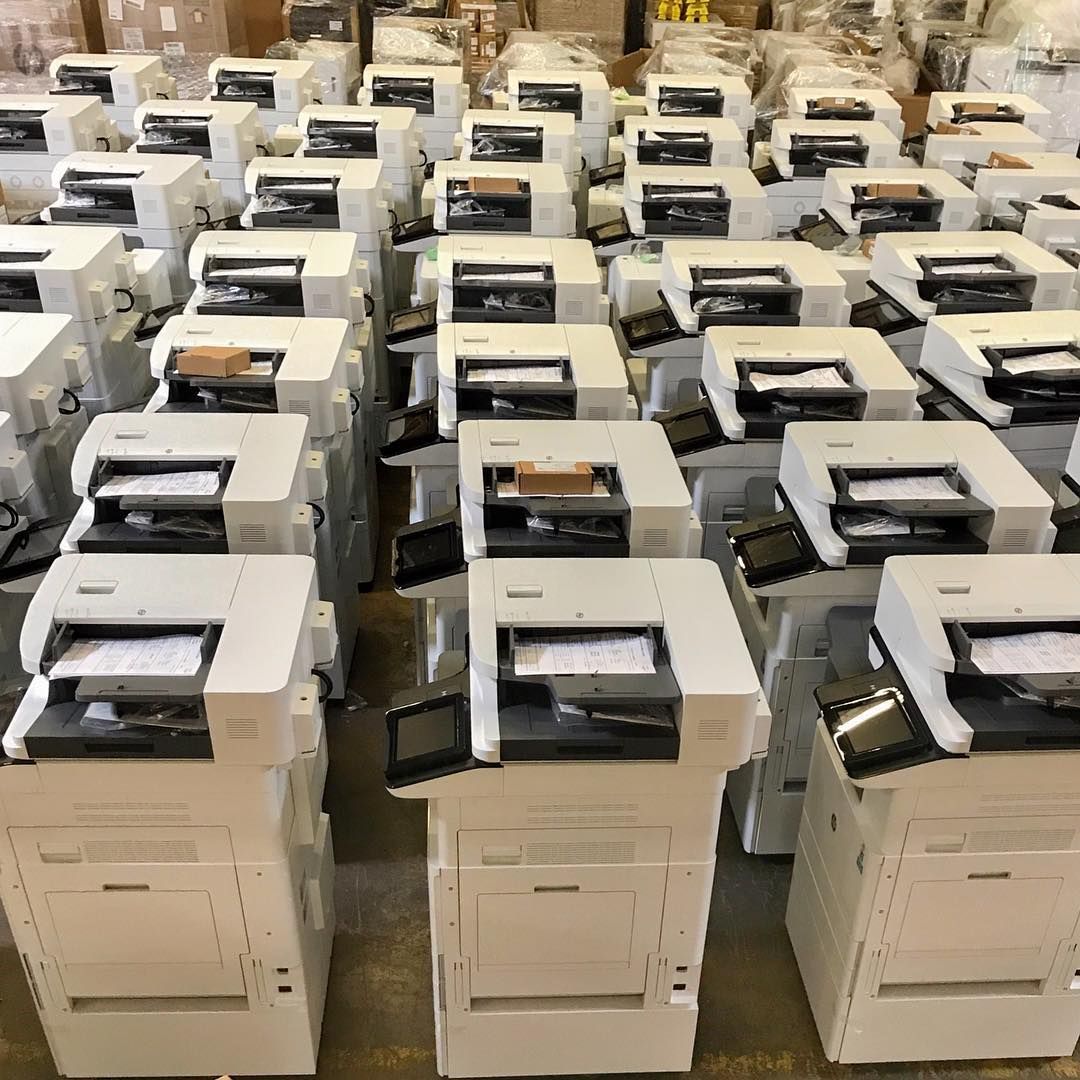 A bunch of printers are lined up in a warehouse