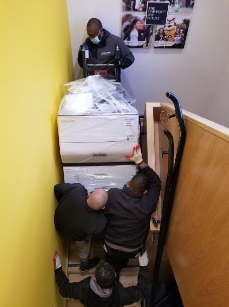 A group of men are delivering a printer