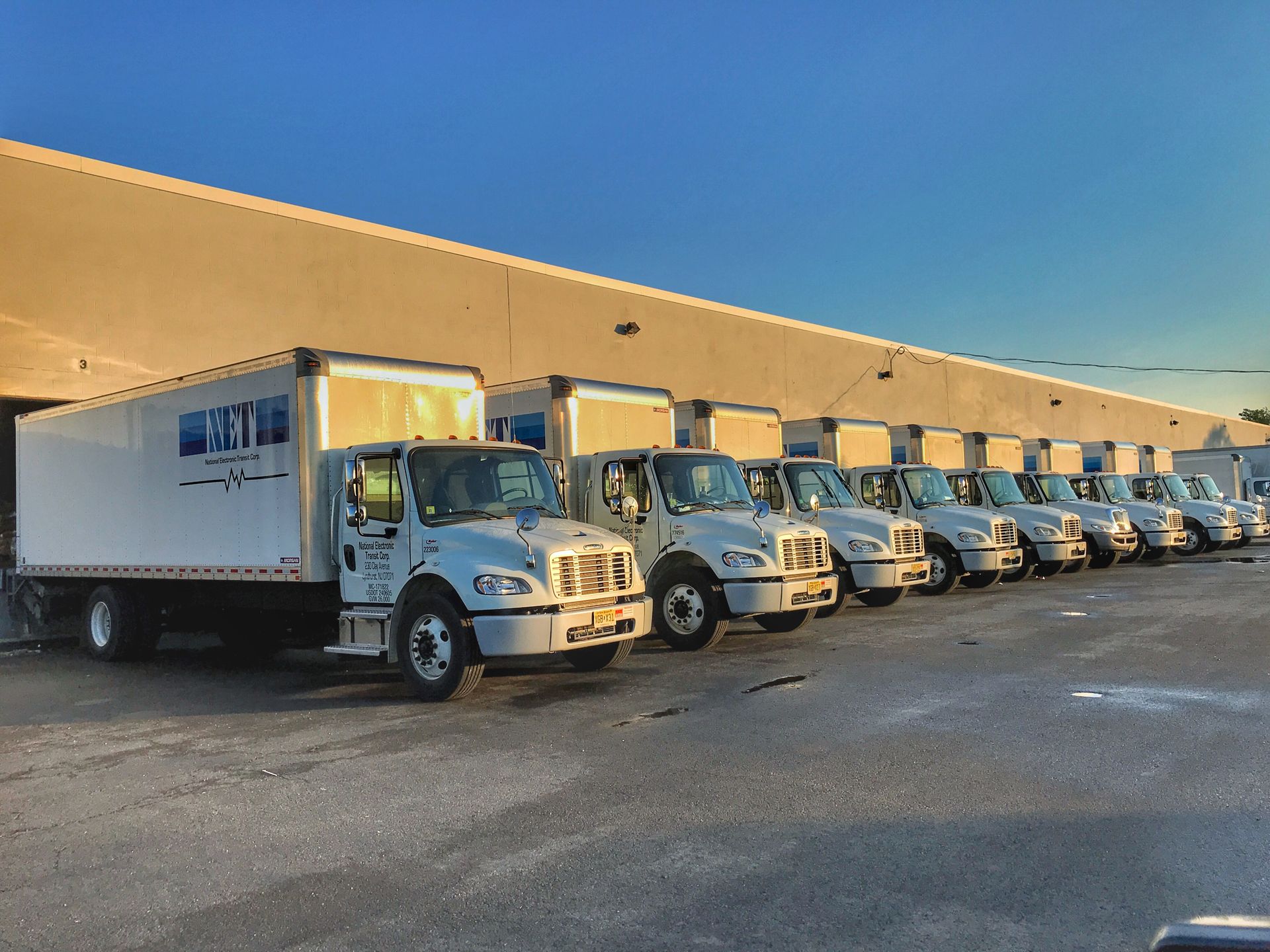A row of white trucks are parked in front of a building