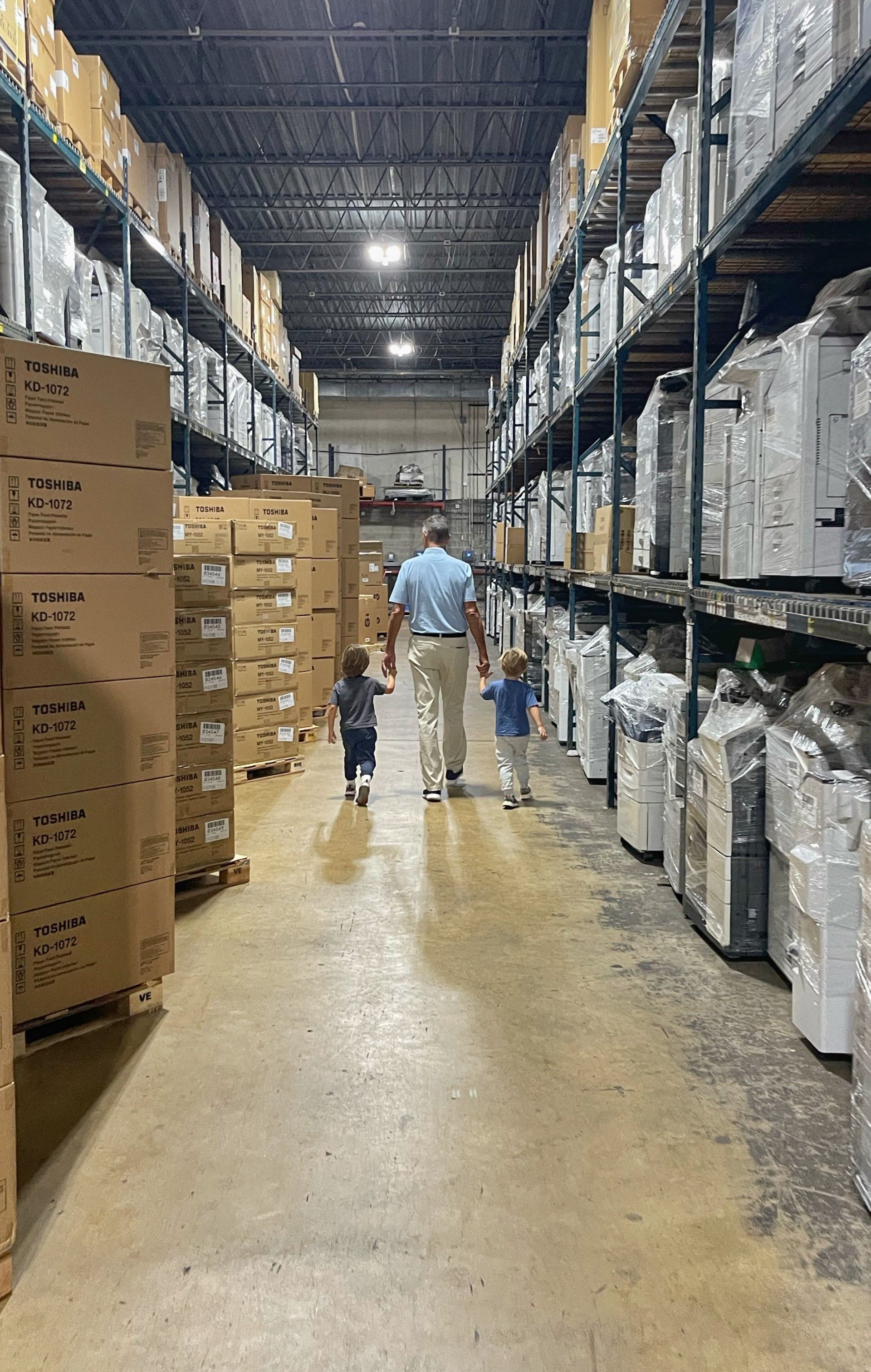 A man and two children are walking through a warehouse