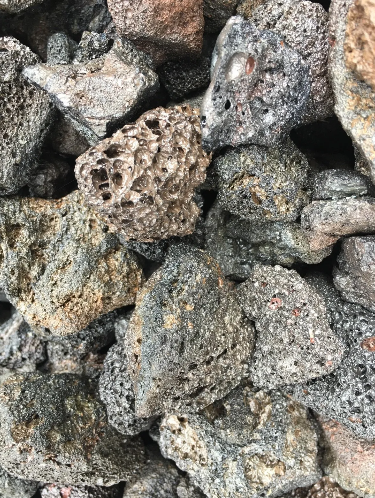 Pile of rough, porous lava rocks, varying shades of gray and brown.