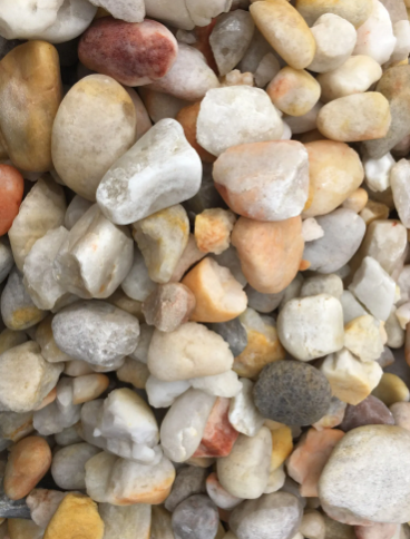Pile of smooth, multicolored river rocks, ranging in colors from beige to orange and gray.