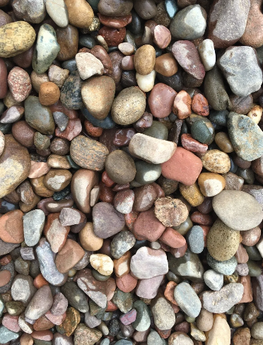 Pile of smooth, colorful river rocks, ranging from red to brown and tan, filling the frame.