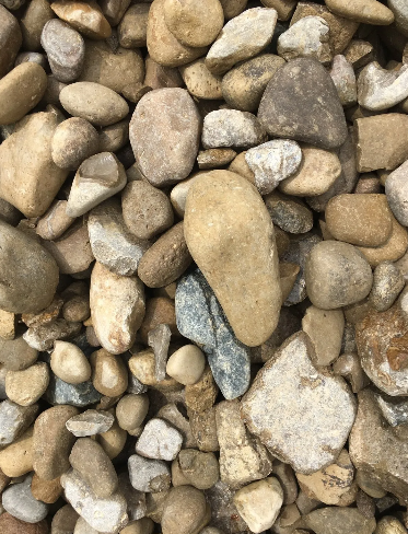 Close-up view of river rocks, varying sizes and shades of tan, brown, and gray.