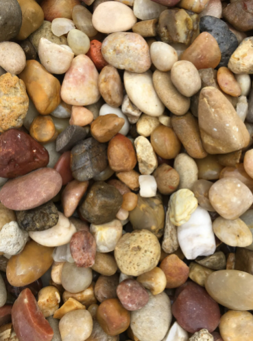Close-up of mixed, smooth river rocks in various colors: brown, tan, red, and white.