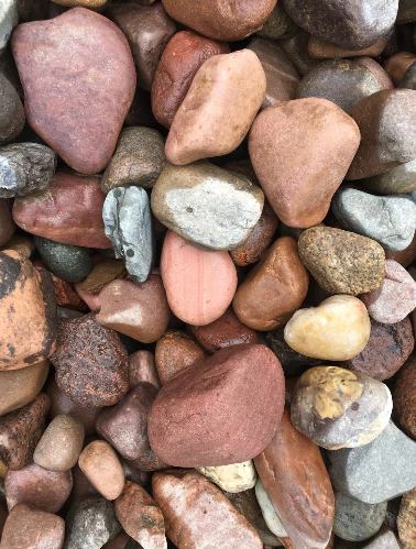 Close-up of a pile of smooth, colorful river rocks, ranging from red to brown and gray.