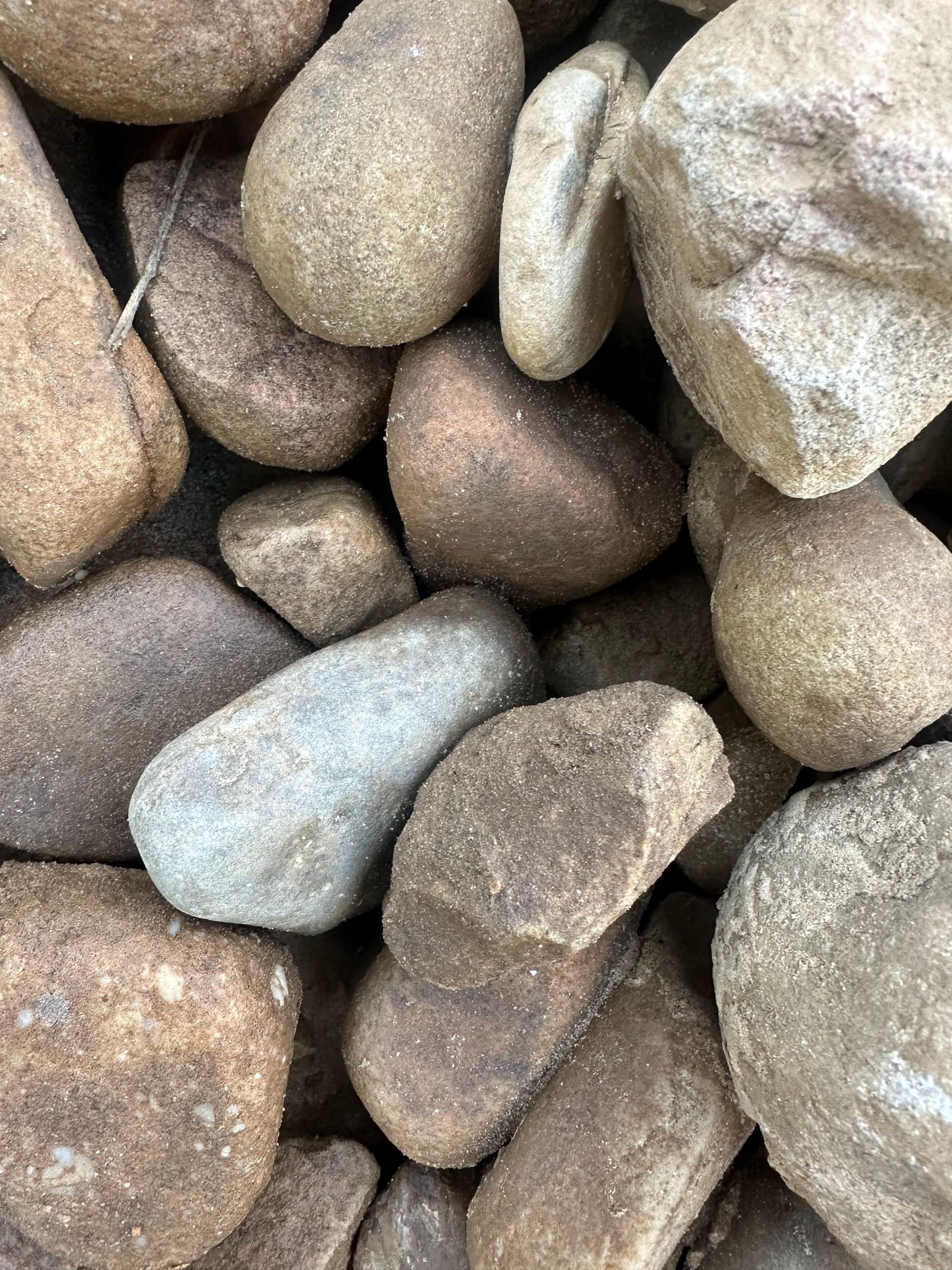Close-up of a pile of rounded, tan and brown river rocks.