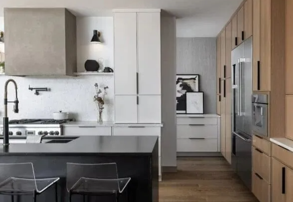 Modern kitchen with black island, white cabinets, and wood accents. Stainless steel appliances.