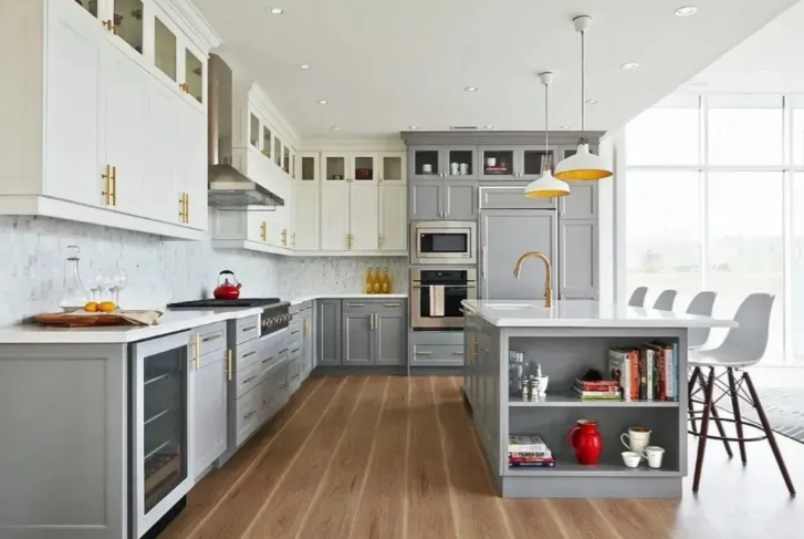 Modern kitchen with gray and white cabinets, wooden floor, island with seating, and stainless steel appliances.