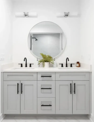 Gray double bathroom vanity with black hardware, round mirror, and plant.