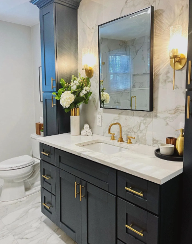 Bathroom with navy blue vanity, gold fixtures, marble backsplash, and large mirror.