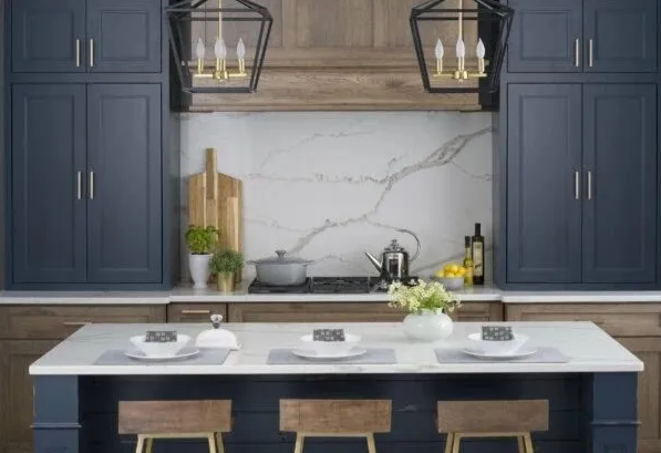 Kitchen with blue cabinets, white countertops, wooden island, and gold light fixtures.