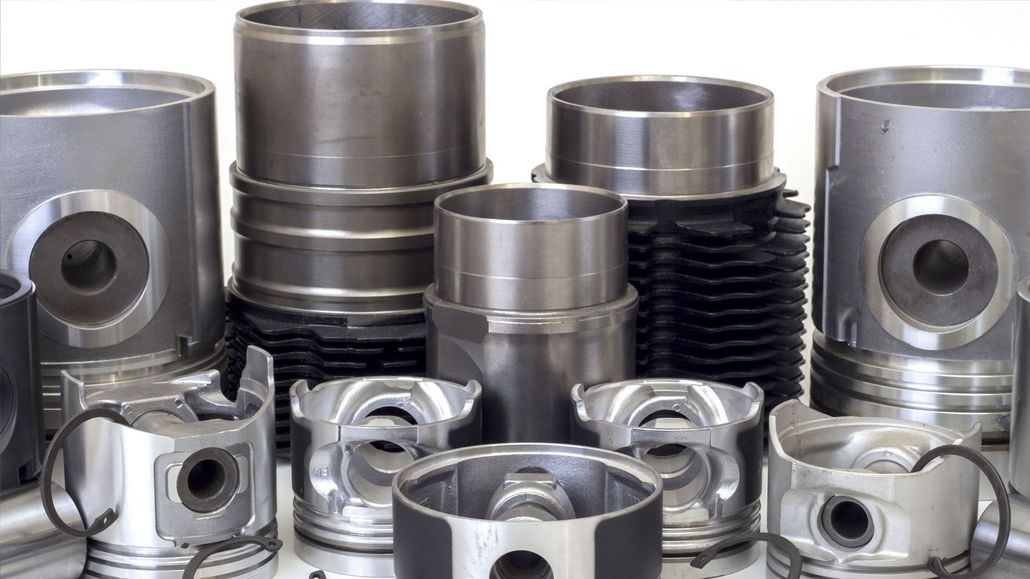 Assorted shiny metal engine pistons and cylinders arranged in a row