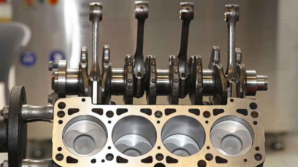 Close-up of an engine block with pistons and crankshaft exposed in a workshop.