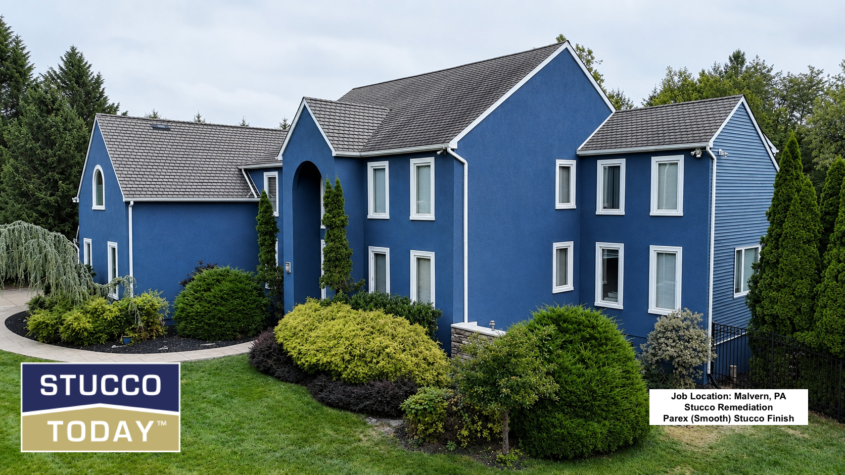 Blue stucco house with gray roof, white trim, and landscaped front yard