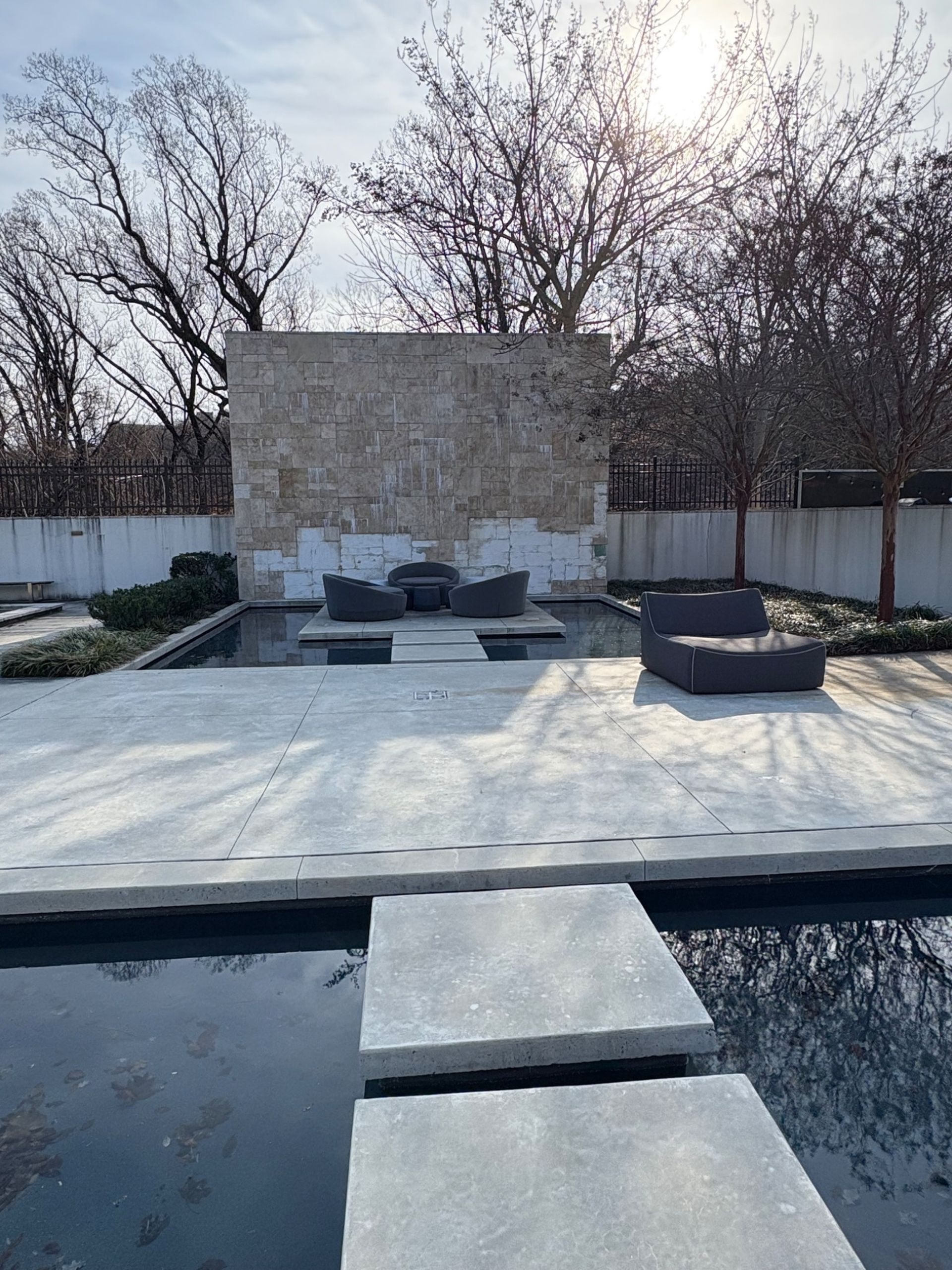 Stone patio with a pool, seating area, and weathered stone wall.