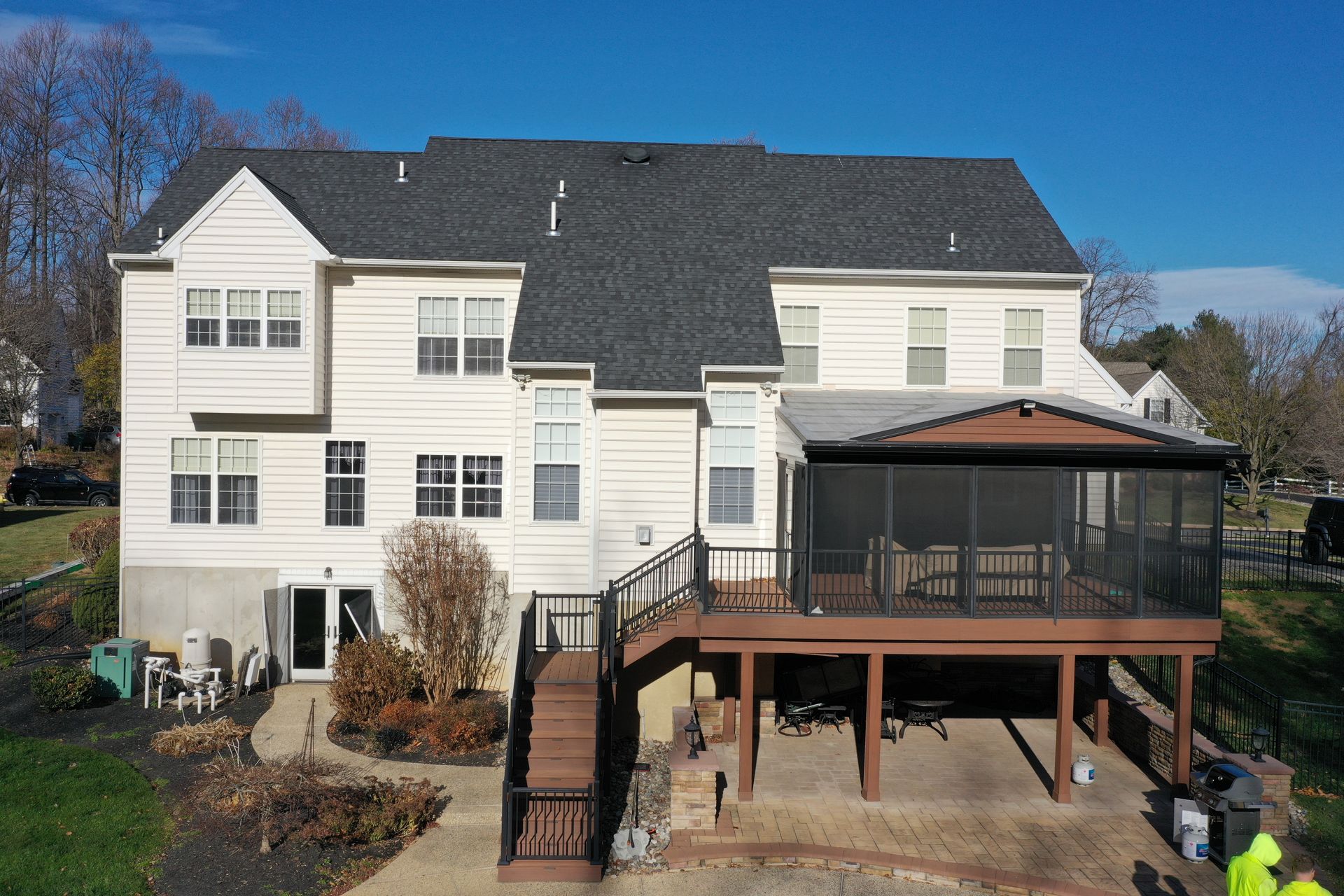 Two-story house with a screened-in porch and wooden deck; blue sky.