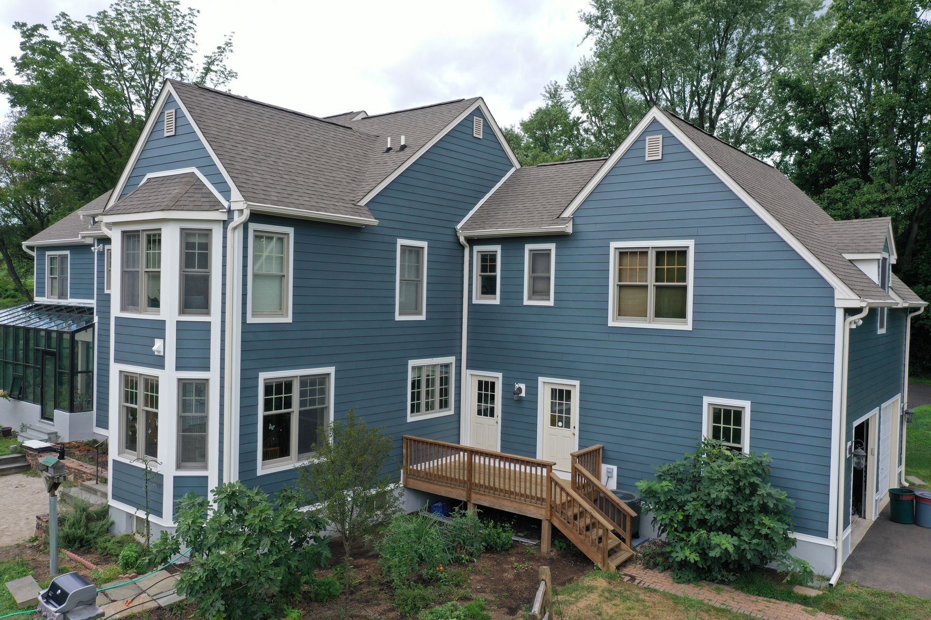 Blue house with brown roof and wooden deck.