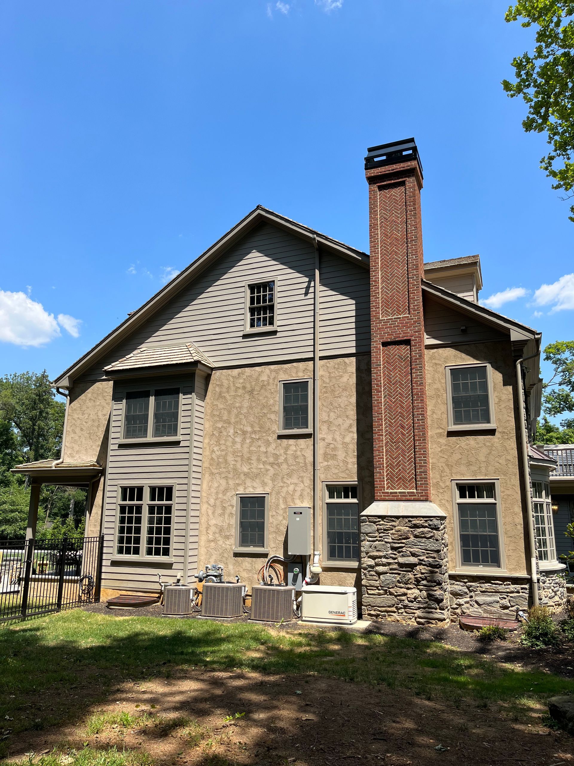 Stone and stucco house with red brick chimney and blue sky backdrop.