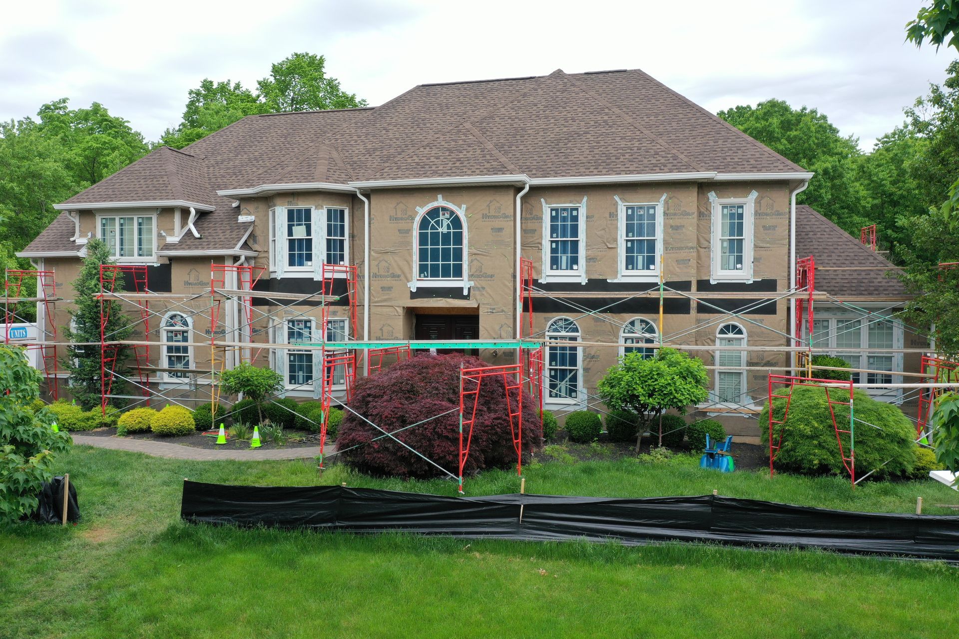 Large brick house under construction with scaffolding and a new roof.