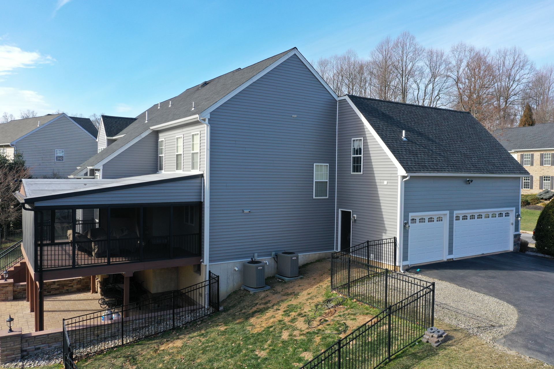 Gray house with a screened porch and attached garage on a sloped lot.