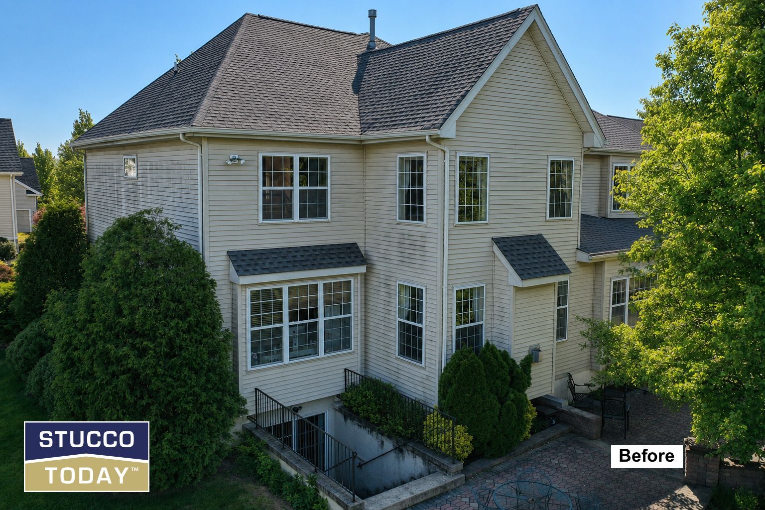 Two-story white stucco house with gray roof and green shrubs, marked “Before” by Stucco Today.