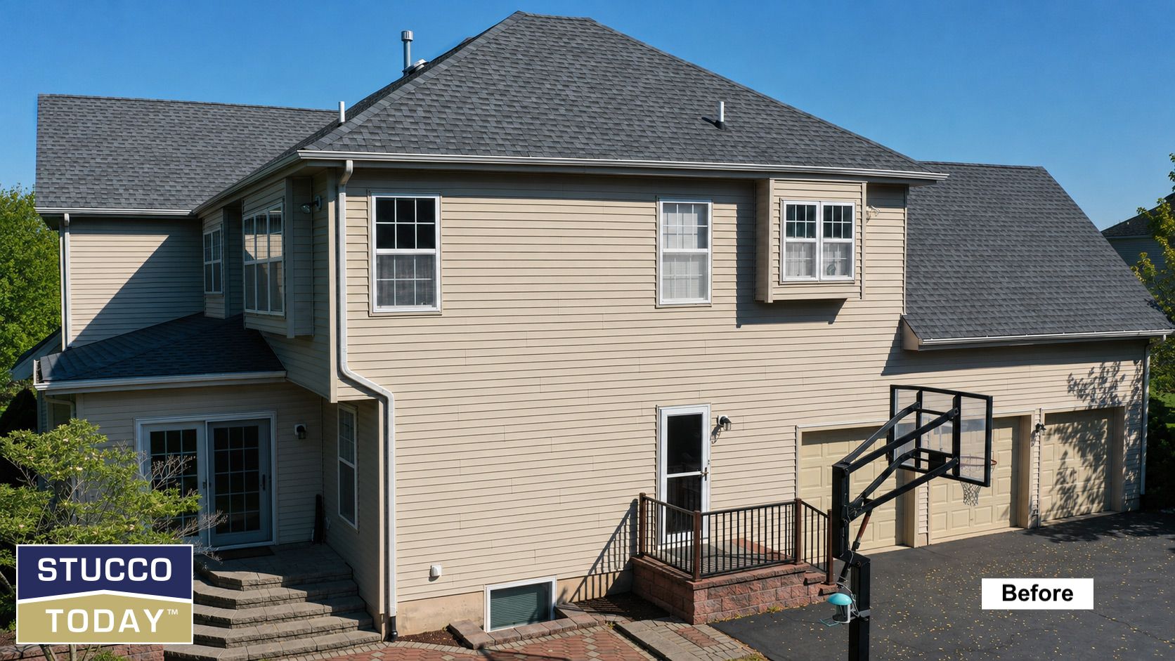 Exterior of a beige two-story house with stucco siding and a dark roof, viewed from the backyard.