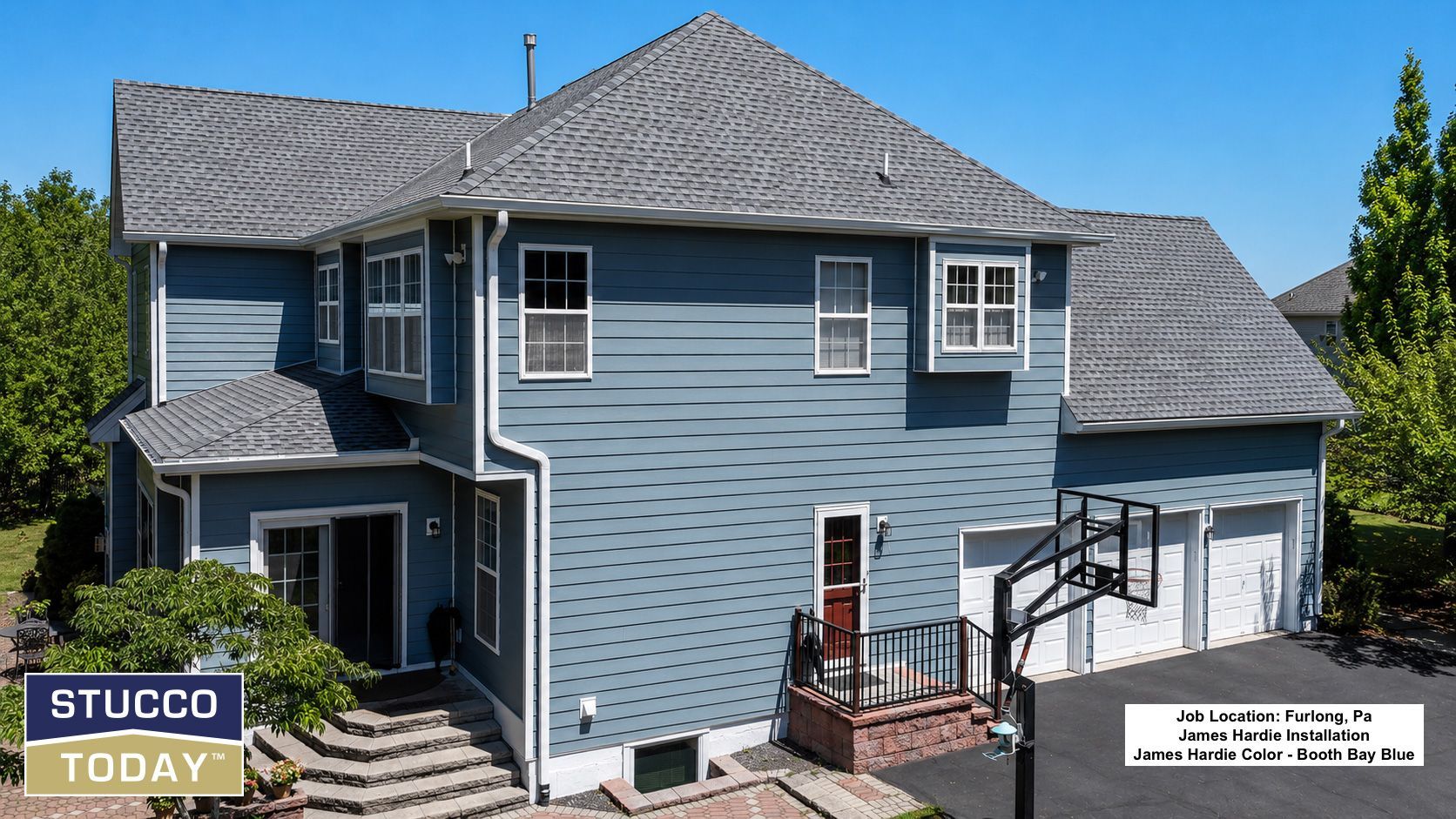 Blue two-story house with gray roof and white trim on a sunny day