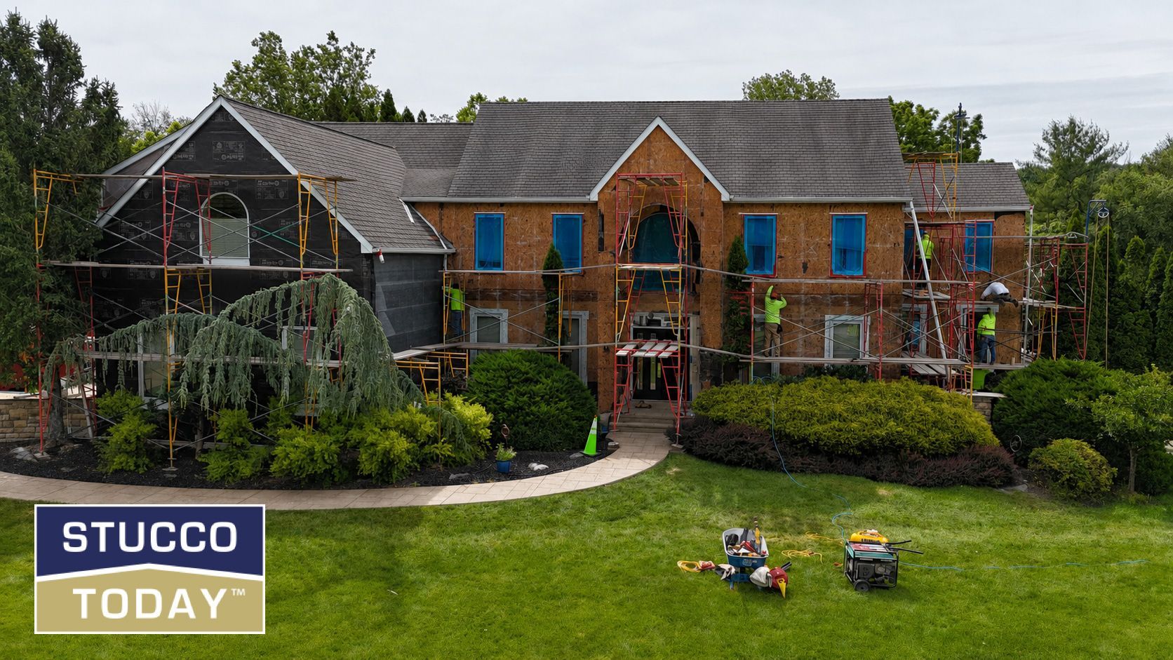 Large brick home with stucco accents, blue window coverings, and landscaped front yard.