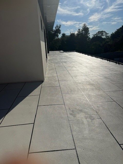 Waterproofed outdoor terrace with white tiles and a smooth, reflective surface.