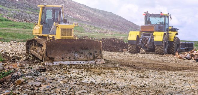Two yellow bulldozers working on rocky terrain.