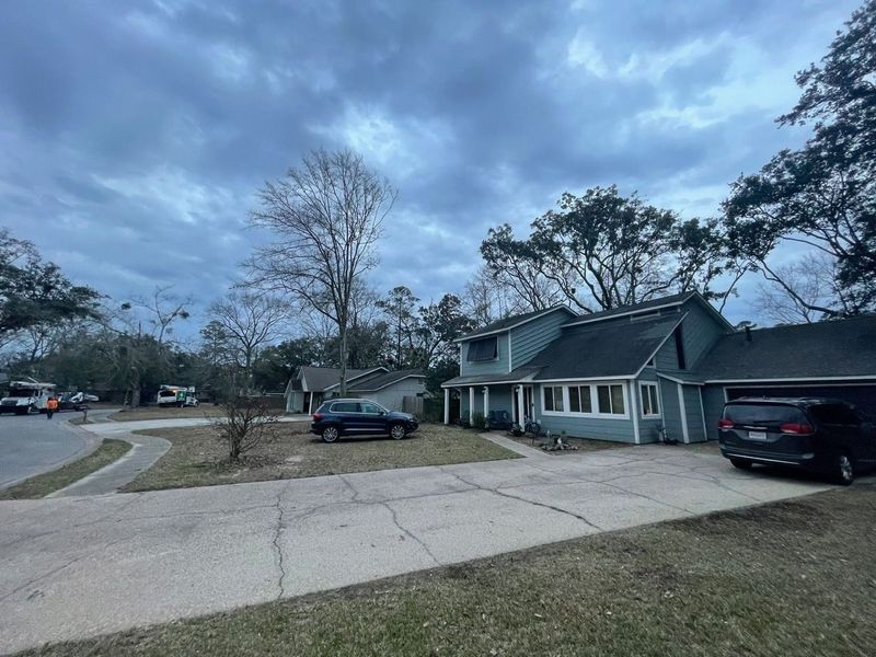 Suburban homes under a cloudy sky; cars parked on the driveway and street.