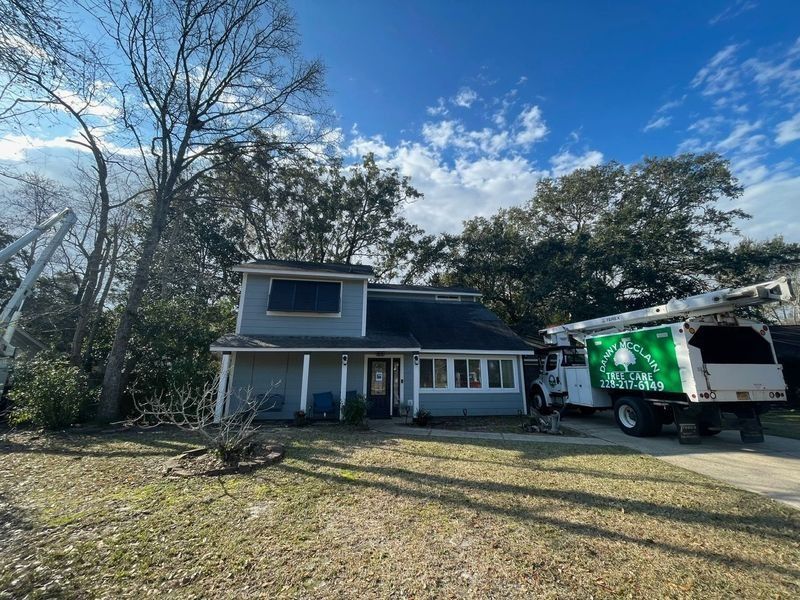 A two-story house with a tree service truck parked in front. Sunny day.