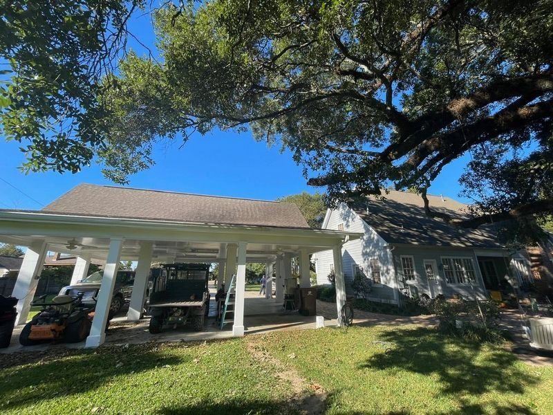 A house with a carport, golf cart, and lush greenery under a blue sky.