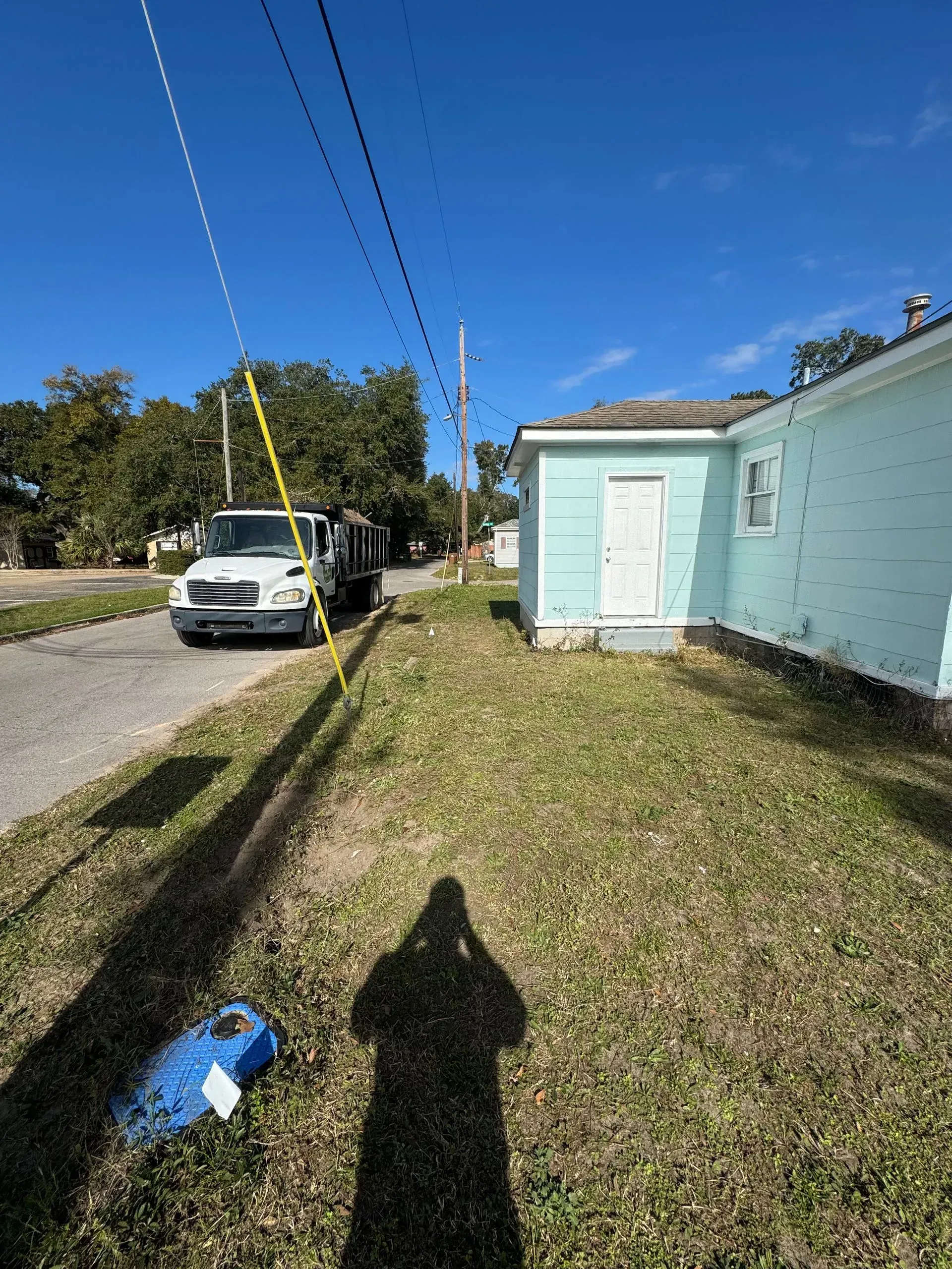 A truck parked near a light blue building and utility pole on a sunny day.