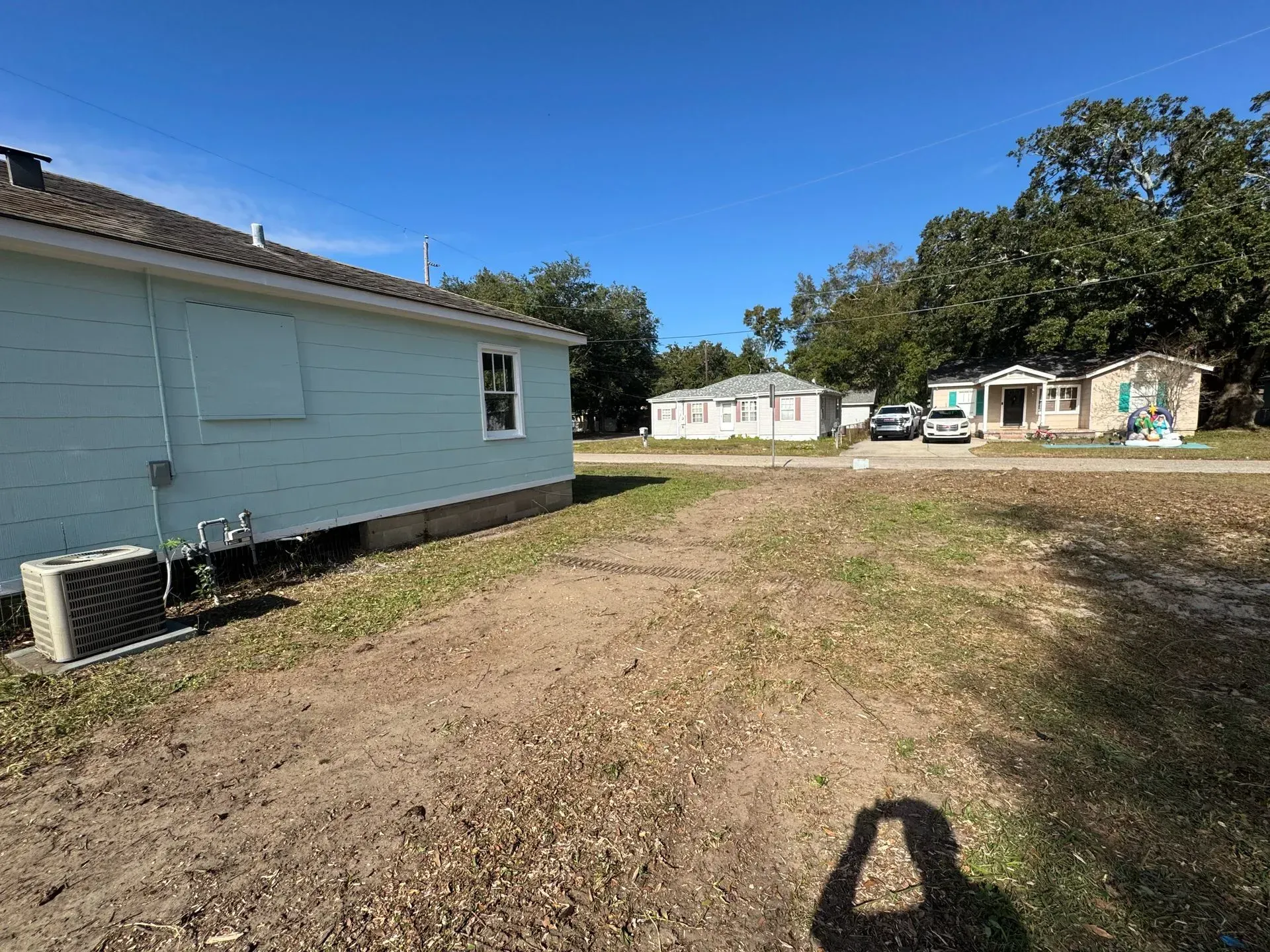 A row of houses on a dirt lot. The sky is blue. The closest house is light blue.