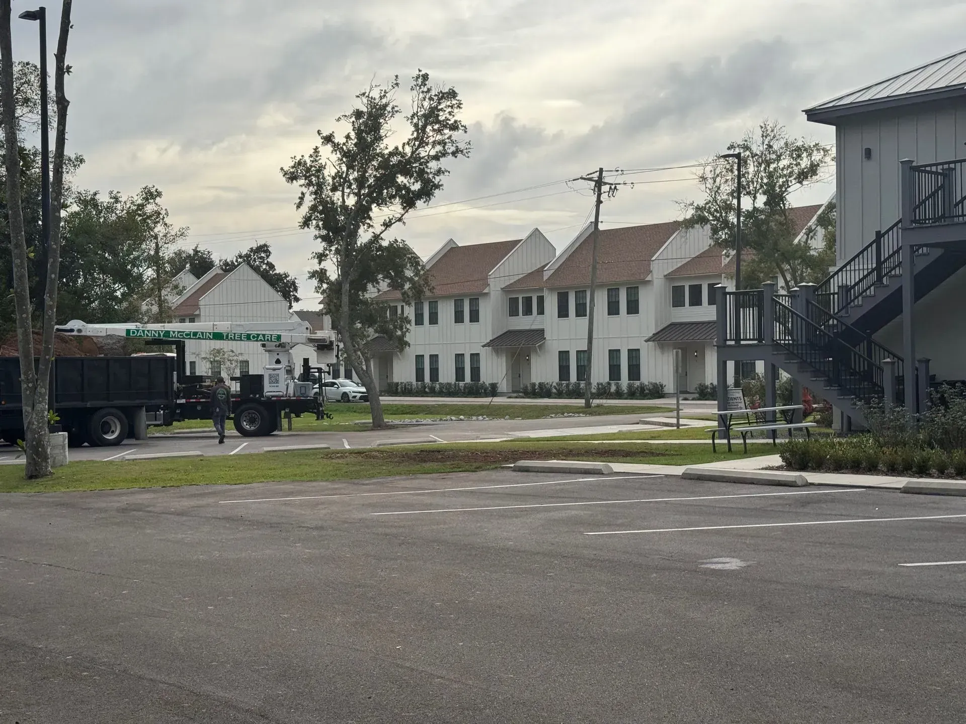 Row of white townhouses with brown roofs; utility truck on a street.