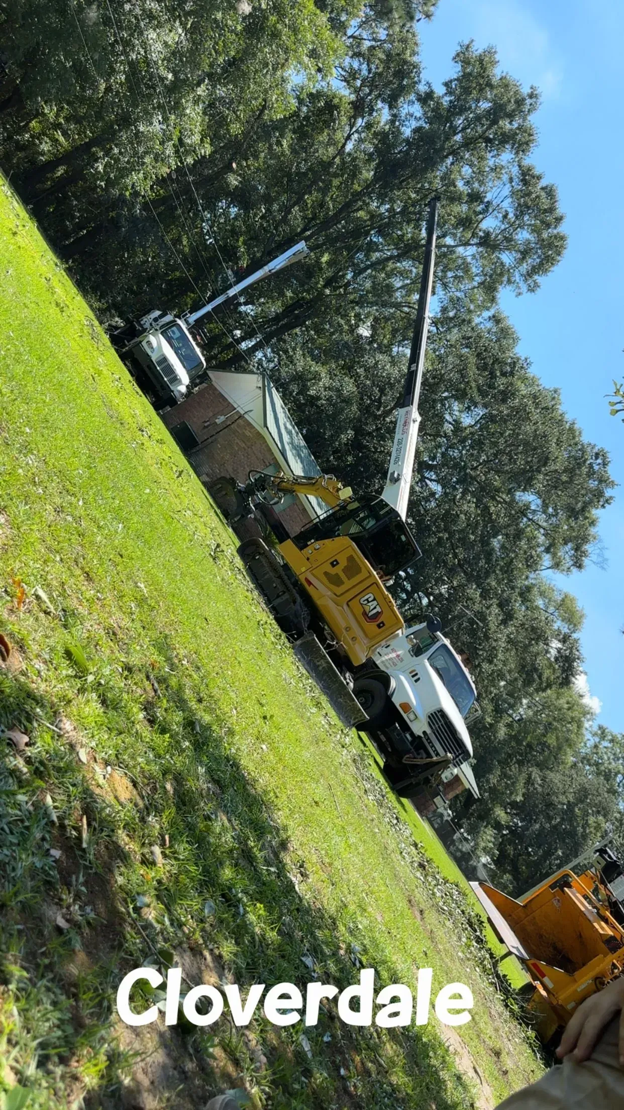 Yellow and white excavator on a grassy hillside in Cloverdale.