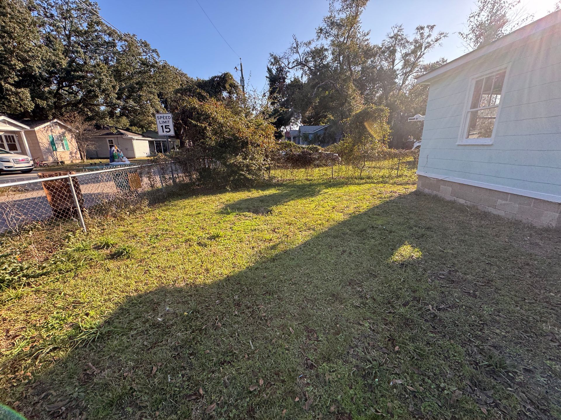 Grassy yard with a house and buildings in the background. Sunny day.