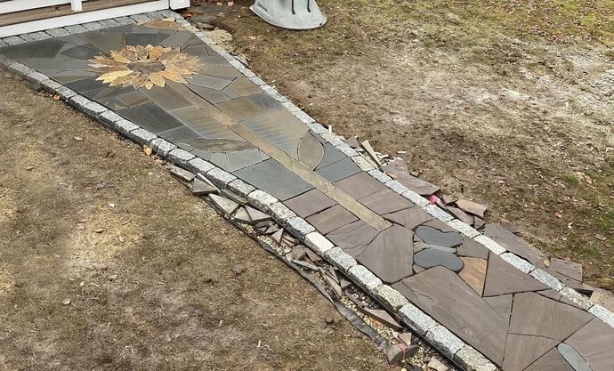 Stone pathway with sunflower mosaic design leading to a white porch.