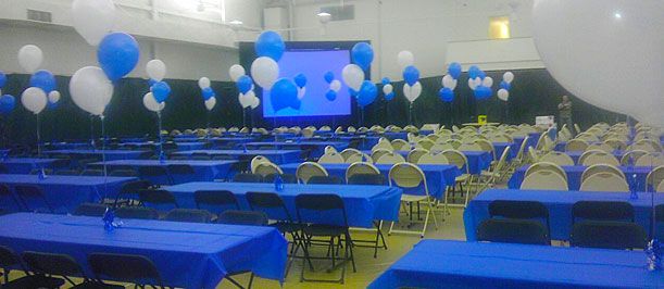 Blue-and-white decorated banquet hall with rows of tables and chairs facing a presentation screen