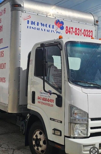 White moving truck with blue and red company lettering and phone number on the side on a street