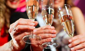 Hands raising champagne flutes in a celebratory toast indoors
