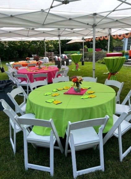 Outdoor party setup with white tents and colorful round tables, including a bright green table in the foreground