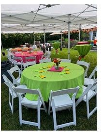 Outdoor event with white tents, green and pink tablecloths, white chairs, and floral centerpieces on grass.
